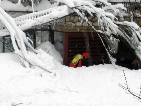 A rescuer clears snow in front of the hotel. 