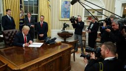 President Donald Trump signs his first executive order in the Oval Office of the White House on January 20, 2017.