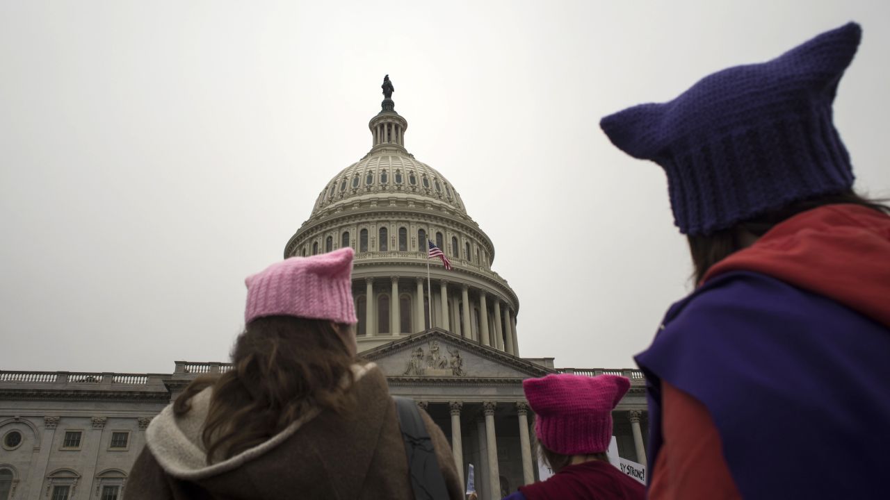 Women with cat hats walk past the Capitol.