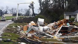 The remains of a house sit in a debris pile along Highway 122 as power line workers repair a downed line on Sunday, January 22, near Barney, Georgia. 