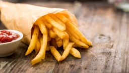 Fresh fried french fries with ketchup on wooden background