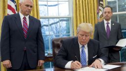  President Donald Trump signs an executive order withdrawing the US from the Trans-Pacific Partnership alongside US Vice President Mike Pence and White House Chief of Staff Reince Priebus in the Oval Office of the White House in Washington, DC, January 23, 2017.