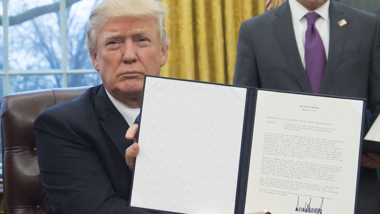 President Donald Trump holds up an executive order withdrawing the US from the Trans-Pacific Partnership after signing it in the Oval Office of the White House in Washington, DC, January 23, 2017.