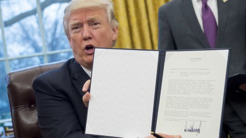 President Donald Trump holds up an executive order withdrawing the US from the Trans-Pacific Partnership after signing it in the Oval Office of the White House in Washington, DC, January 23, 2017.
