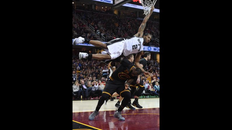 San Antonio's Kawhi Leonard hangs onto the net to avoid landing on Cleveland's LeBron James during an NBA basketball game in Cleveland on Saturday, January 21. Leonard had a career-high 41 points as San Antonio won in overtime 118-115.
