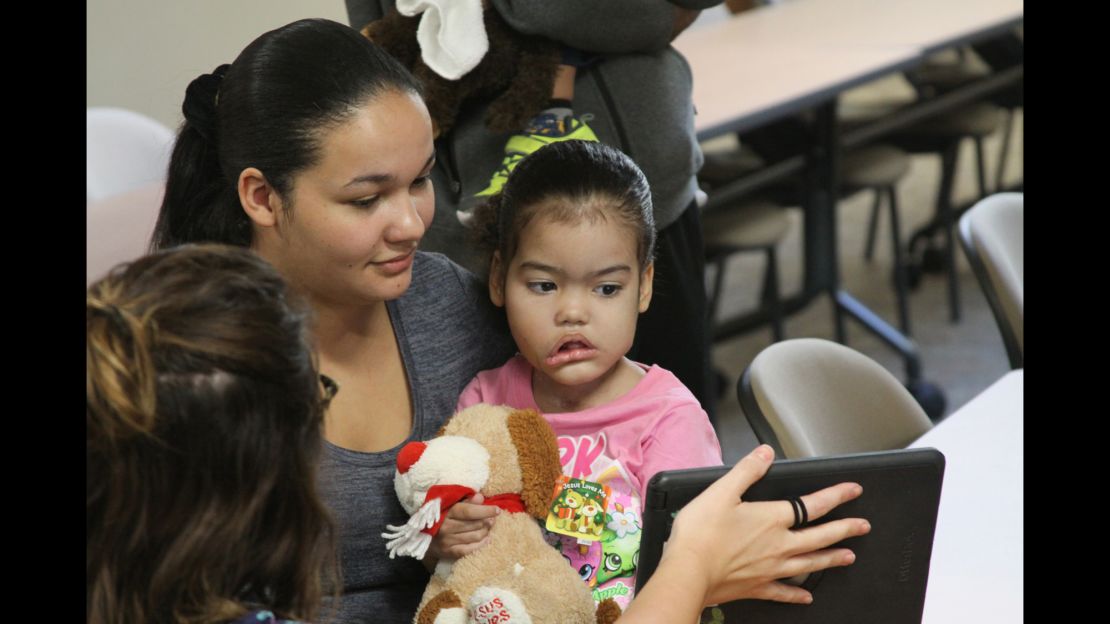Melyssa Braga watches a video with her mother, Caroline, and a nurse.