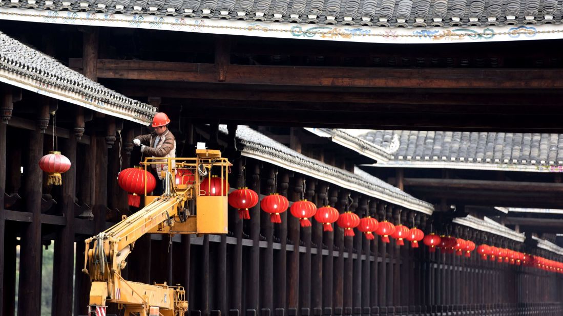 A worker hangs red lanterns on a bridge in China's Sanjiang Dong Autonomous County on Monday, January 23.