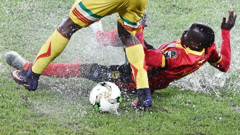 Uganda's Godfrey Walusimbi challenges Mali midfielder Yves Bissouma on the Stade d'Oyem's rain-soaked pitch.