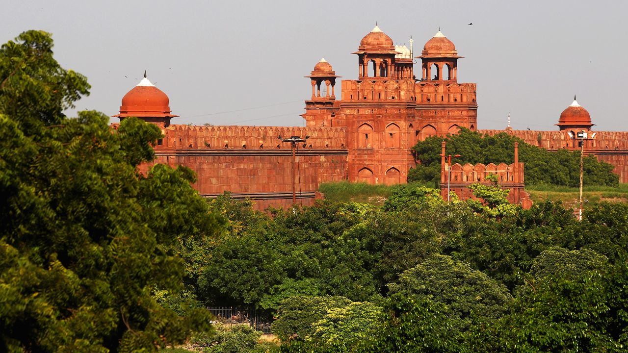The Red Fort is seen through the greenery of an early fall day in Delhi.