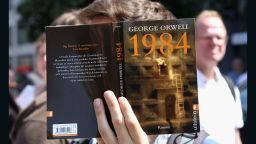 BERLIN, GERMANY - AUGUST 01:  A protester holds a German translation of George Orwell's book '1984' as he demonstrates for journalists' rights on August 1, 2015 in Berlin, Germany. After two German journalists, Andre Meister and Markus Beckedahl, reported that the German government planned to increase online surveillance, an investigation for treason, the first such case in the country against journalists in over 50 years, was brought against them and has since been suspended by the country's prosecutor-general after negative reactions from other journalists and politicians due to the implications of stifling the freedom of the press.  (Photo by Adam Berry/Getty Images)