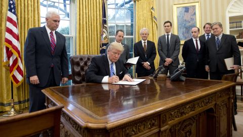 President Donald Trump signs the first of three Executive Orders in the Oval Office of the White House in Washington, DC on Monday, January 23, 2017.