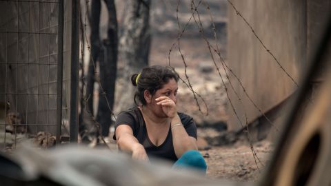 A woman wipes tears amid the remains of Santa Olga, a small town ravaged by the fires. 