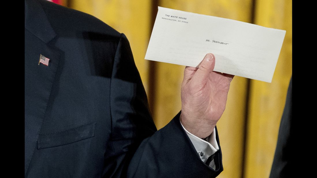 Trump holds up a letter Sunday, January 22, that was left for him by former President Barack Obama.