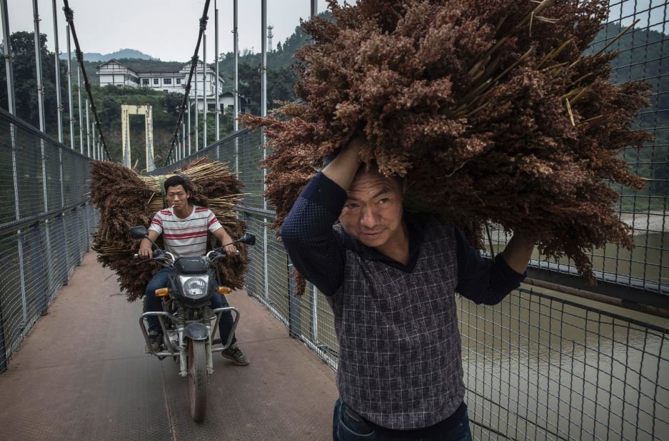 <strong>Maotai, China:</strong> Chinese farmers carry sorghum grain across a bridge in Maotai. Sitting along China's Chishui River in the southwestern province of Guizhou, the town produces over half of the country's baijiu. 