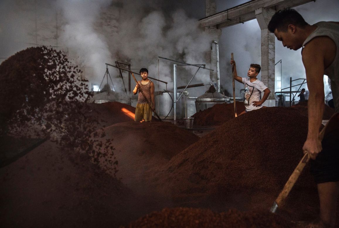 <strong>Fermentation: </strong>Chinese workers toss sorghum, one of the key ingredients used for locally made baijiu, in preparation for the first step of fermentation. 