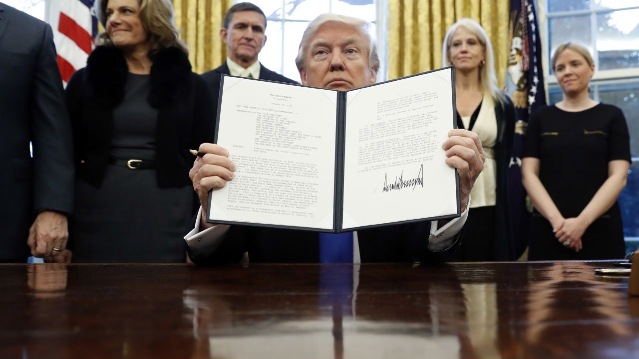 President Donald Trump holds up a signed executive memorandum calling on the Pentagon to "develop a comprehensive plan to defeat ISIS." 
