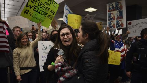 A detained traveler reacts after being cleared through