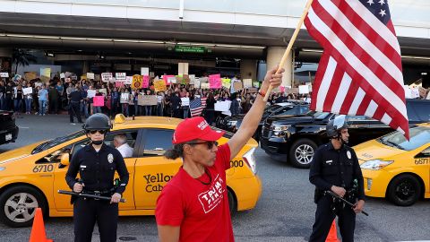 A President Trump supporter waves a US flag at Los Angeles International Airport during a demonstration Sunday over the immigration ban.