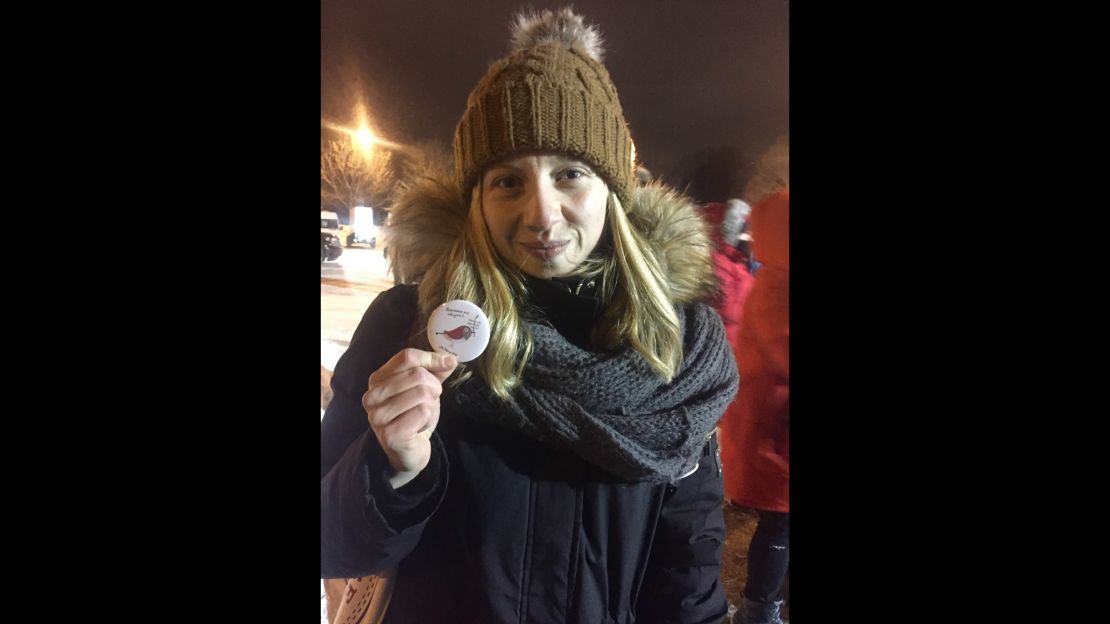 Milena Babin poses with a button from the Intercultural Center of Québec. Babin says the inscription in Arabic at the bottom means welcome to Quebec.