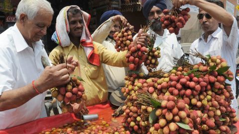 A fruit vendor offers lychees to customers from his roadside stall in Amritsar, India.