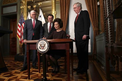 Elaine Chao, Trump's pick for transportation secretary, signs the affidavit of appointment during her swearing-in ceremony in Washington on Tuesday, January 31. Chao is joined, from left, by Pence; her father, James Chao; and her husband, Senate Majority Leader Mitch McConnell.