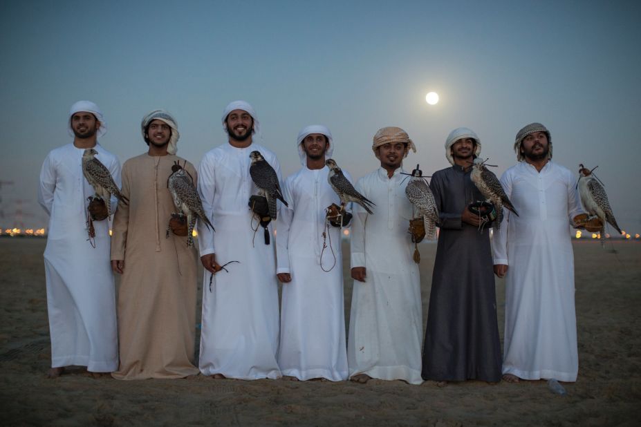 Emirati men pose with their Falcons after an evening training session. Groups of friends regularly come together in the evenings to meet and train their birds where the practice becomes more about camaraderie and sharing knowledge than subsistence.