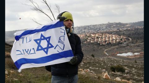 An Israeli settler holds a flag with slogans at the Amona outpost, northeast of Ramallah, on February 1, 2017.