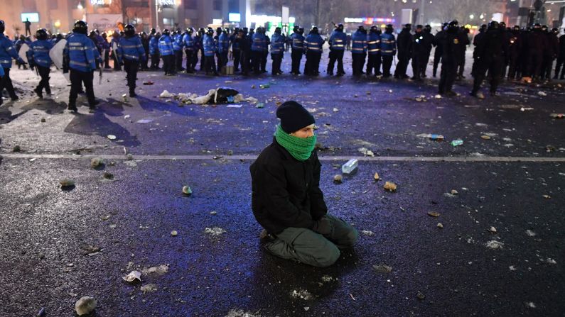 A protester kneels near a police line on February 1 in Bucharest.