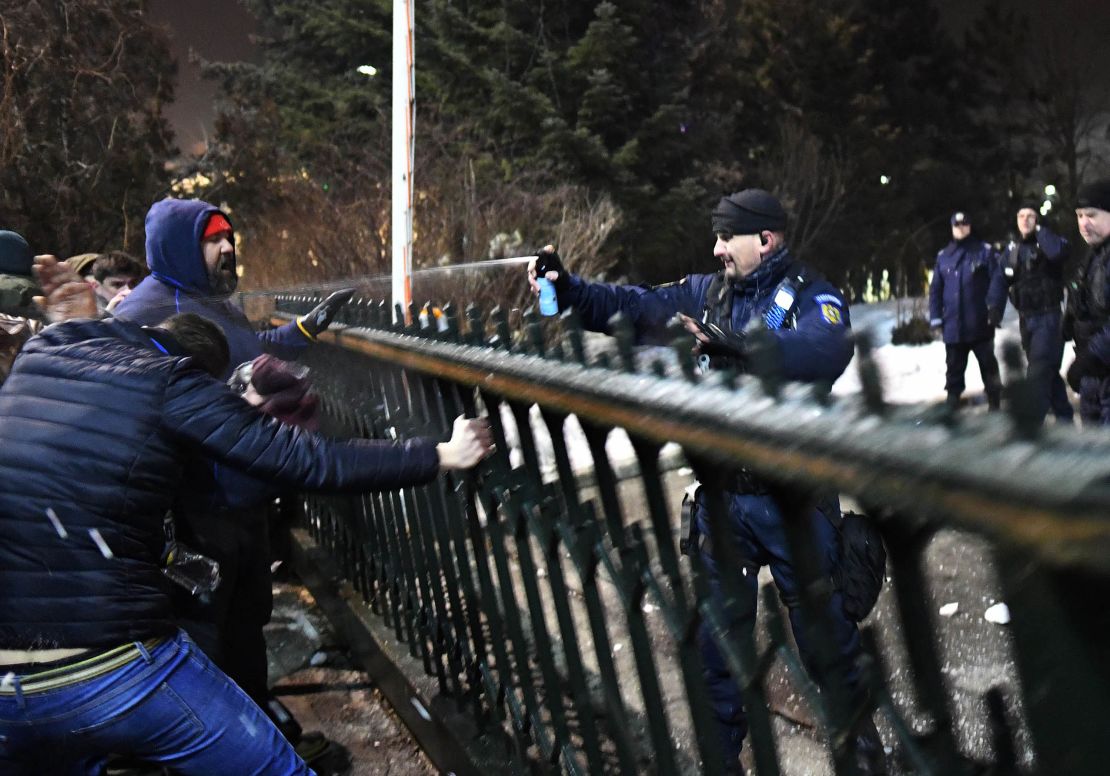 An officer uses pepper spray on protesters trying to enter government headquarters Tuesday.