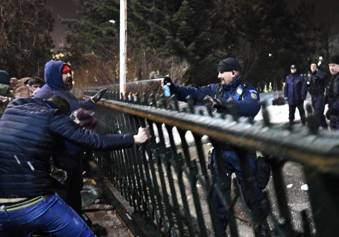 An officer uses pepper spray on demonstrators trying to gain access to a government building in Bucharest on Tuesday, January 31. 