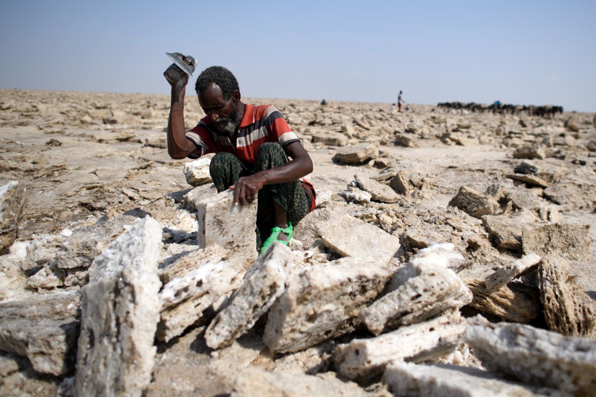  A salt miner works in the heat as he digs out salt blocks by hand. Miners use hoes and axes to carve out the "white gold."