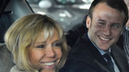 Former French Economy Minister Emmanuel Macron (R) smiles next to his wife Brigitte Macron as they arrive at the station of Le Mans prior to a political meeting on October 11, 2016. / AFP / JEAN-FRANCOIS MONIER        (Photo credit should read JEAN-FRANCOIS MONIER/AFP/Getty Images)