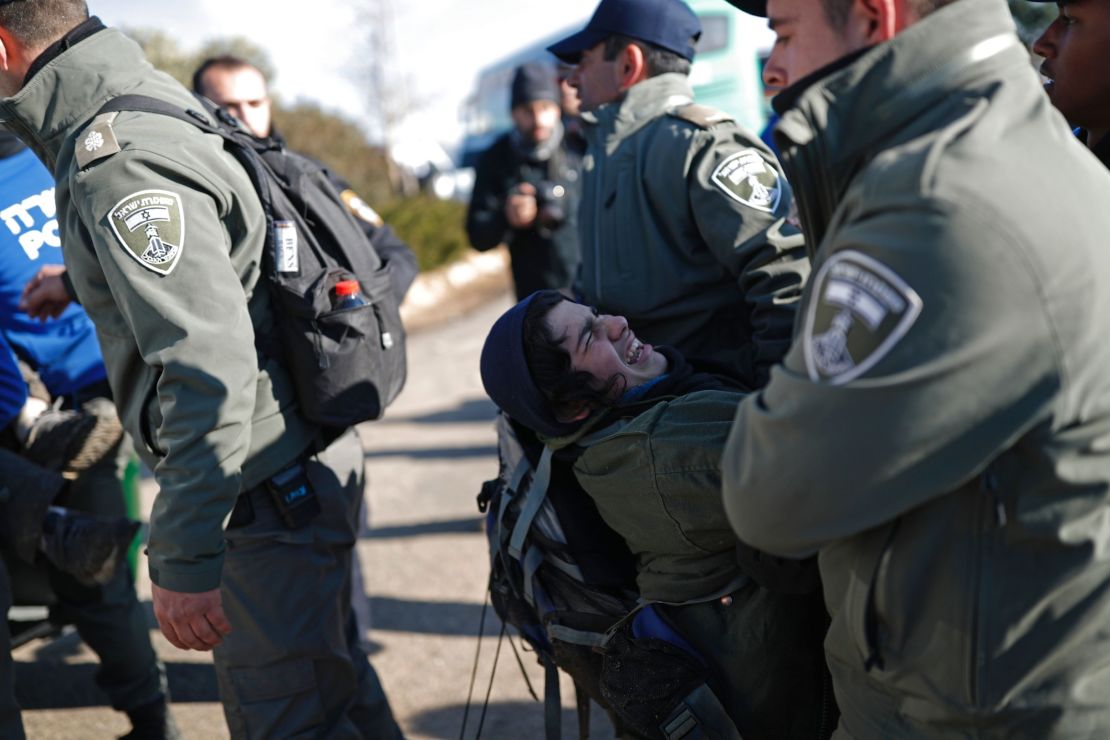 Israeli security forces carry an Israeli settler on the second day of an operation to evict occupants from the West Bank outpost of Amona on February 2, 2017.