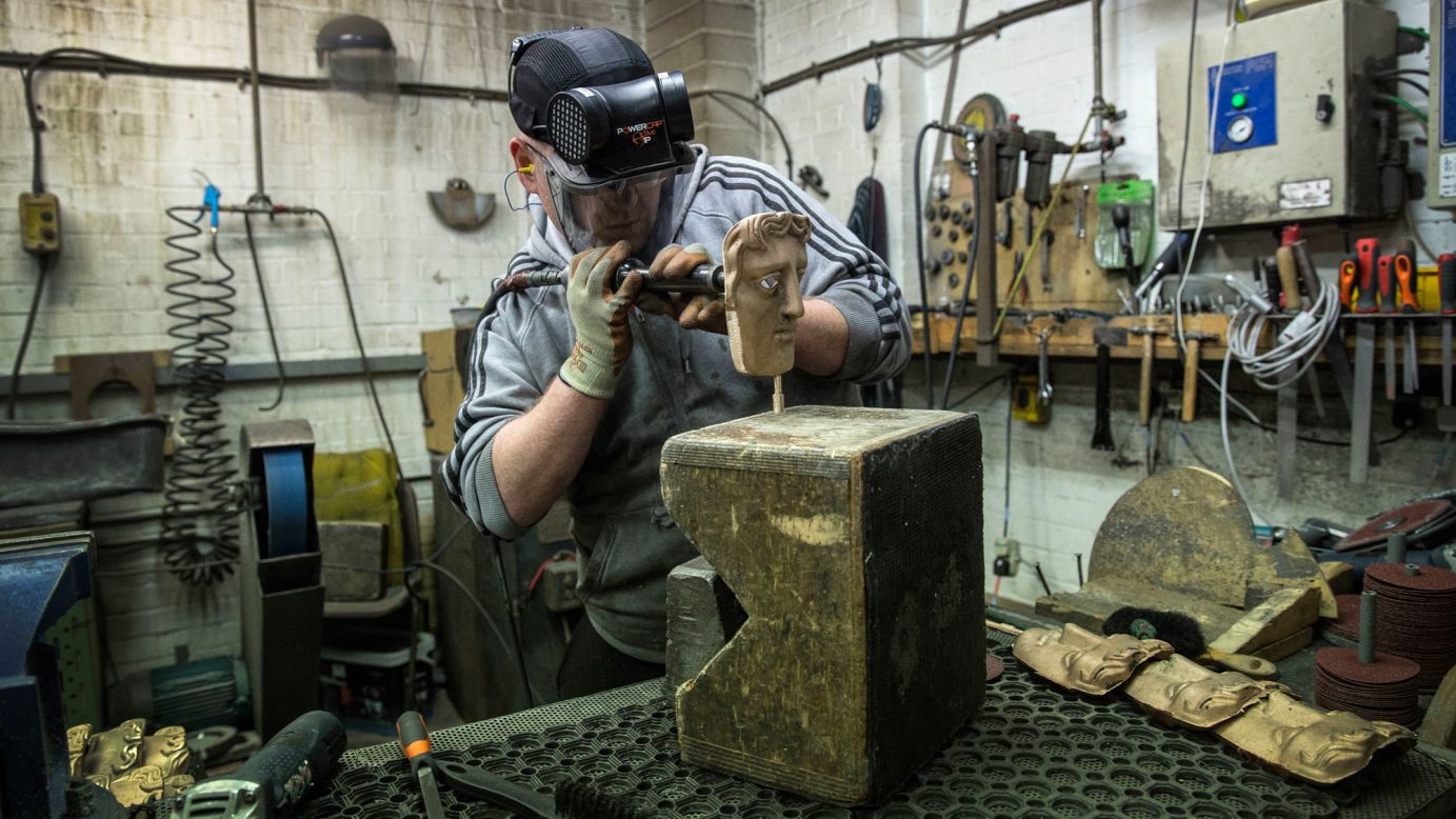 A fettler works on a bronze alloy British Academy of Film and Television Arts (BAFTA) mask at a foundry in West Drayton, England, on Tuesday, January 31, ahead of the award ceremony set to take place later this month. The iconic BAFTA mask was designed in 1955 by US sculptor Mitzi Cunliffe.