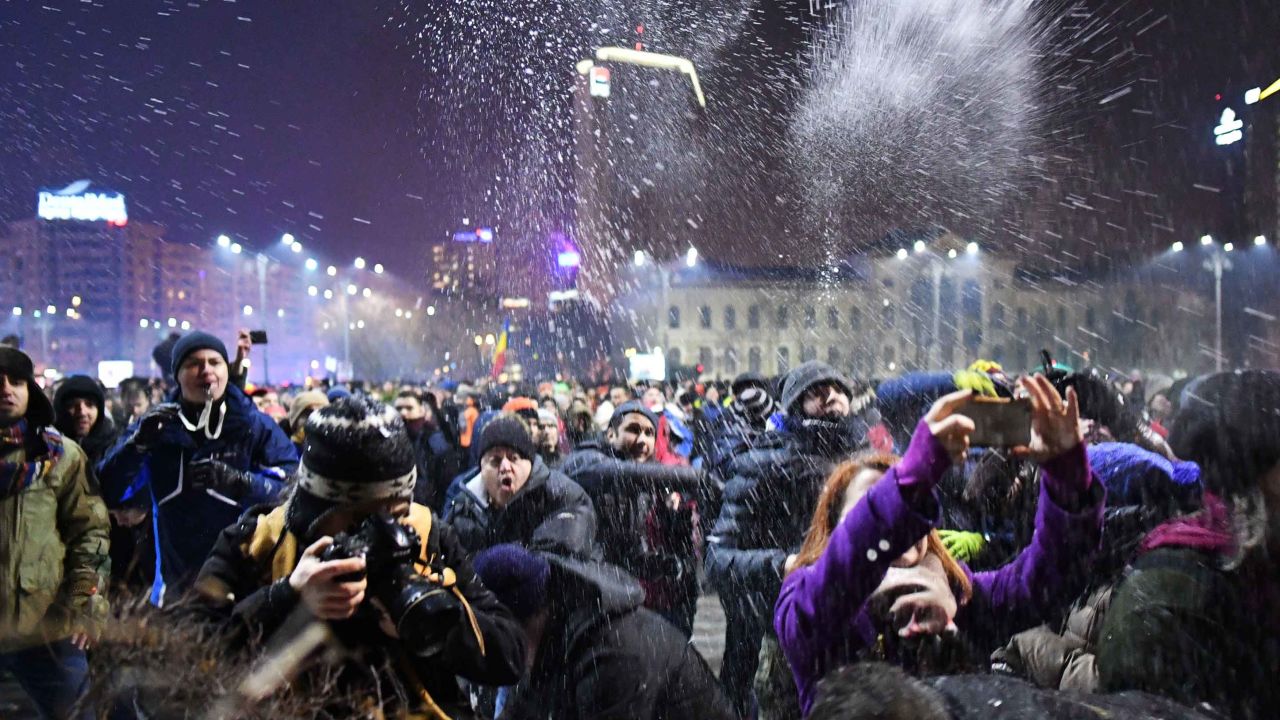 People throw snow toward  police guarding government headquarters in Bucharest.