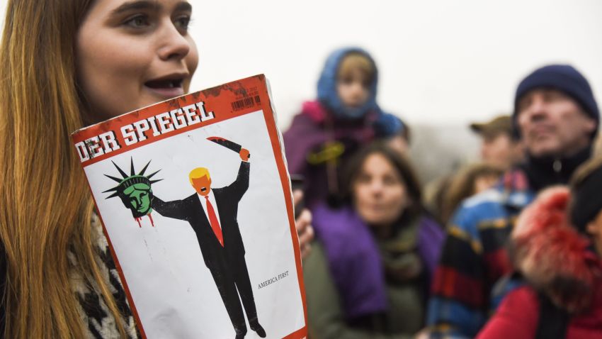 A young woman holds the last edition of "Der Spiegel" magazine with a cover designed by Edel Rodriguez, as she protests against the travel ban imposed by US President Donald Trump, on February 4, 2017, in Berlin. / AFP / ODD ANDERSEN        (Photo credit should read ODD ANDERSEN/AFP/Getty Images)