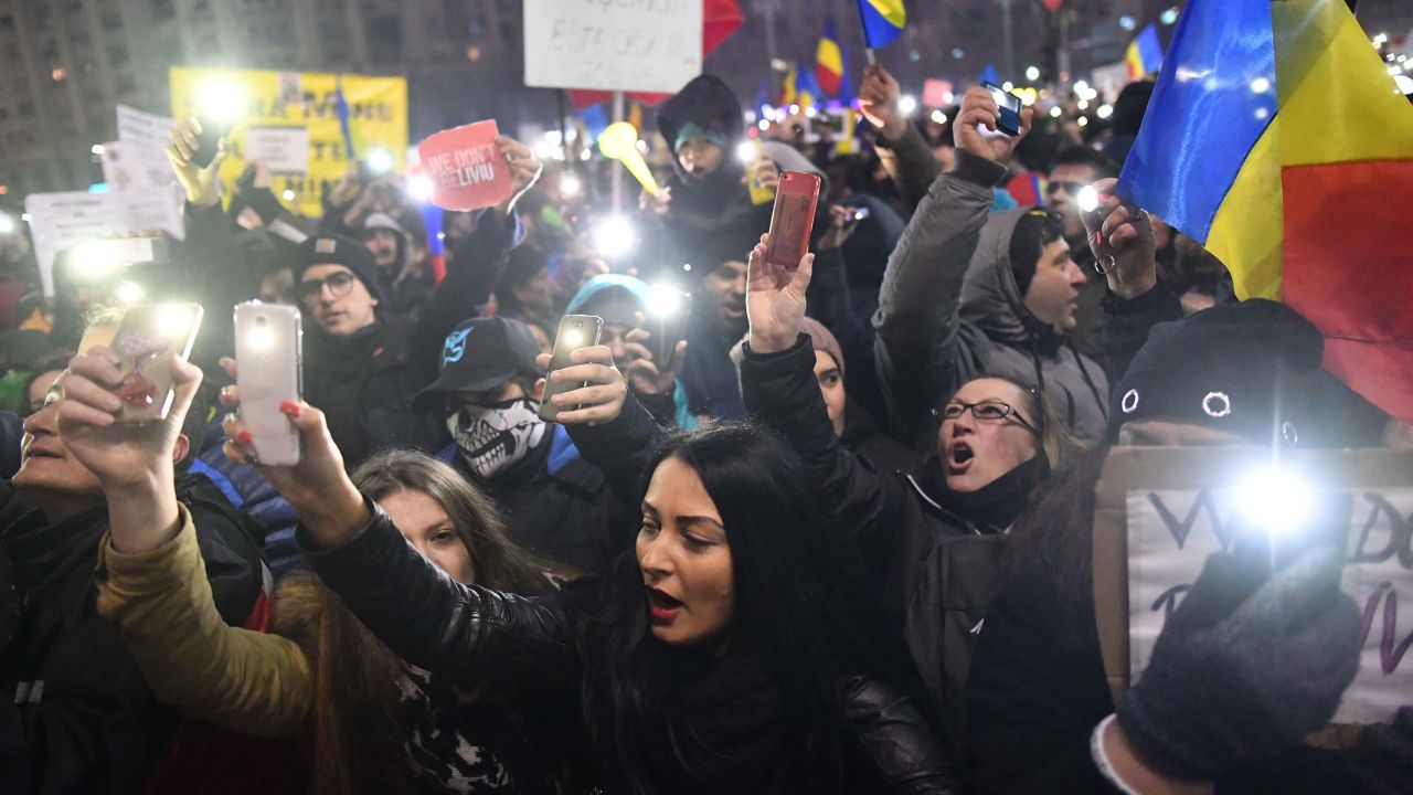 Protesters shine their mobile phone lights as they protest in front of government buildings Sunday