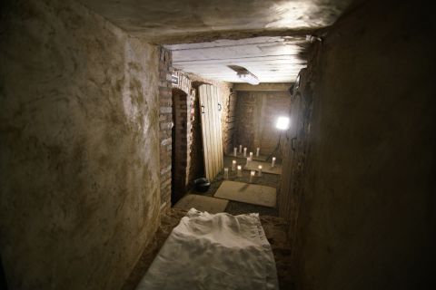 The vault is reached down a narrow flight of steps, through a corridor replete with old pipes at head height, then by scrambling through a hole in a thick foundation wall built in 1846. 