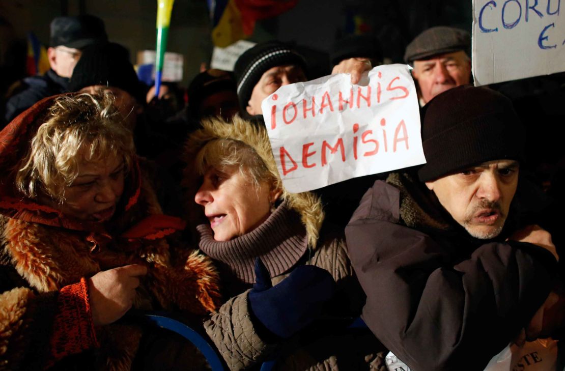 Protests continued in Bucharest on Monday evening - this demonstrator's sign calls for the president to quit.