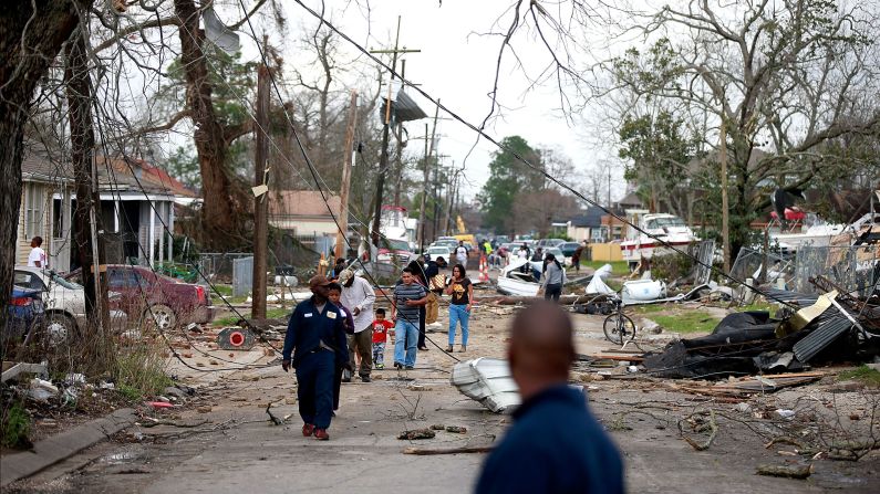 People walk down a street in New Orleans after a tornado touched down in the eastern part of the city on Tuesday, February 7.