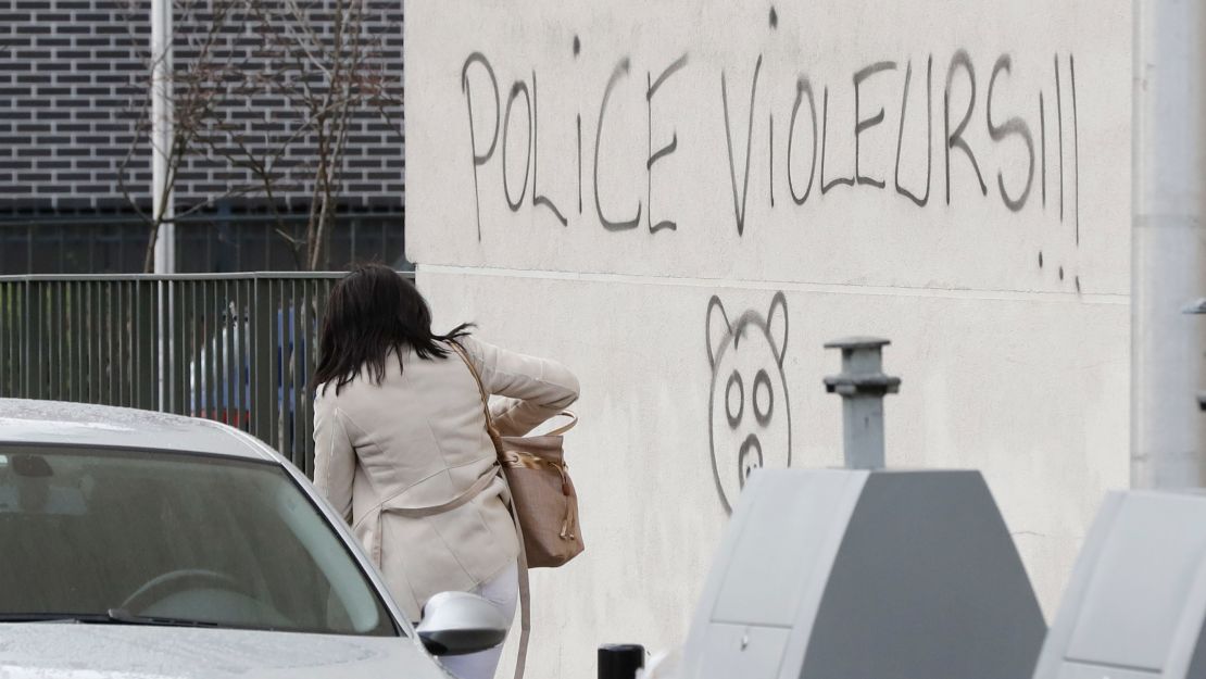 A woman walks next to graffiti reading "police rapists."