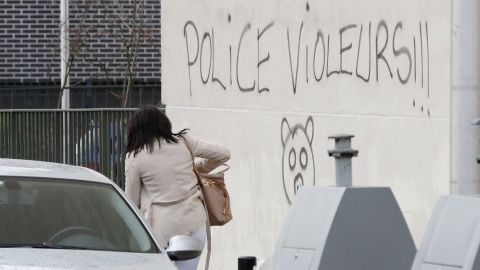 A woman walks next to graffiti reading "police rapists."