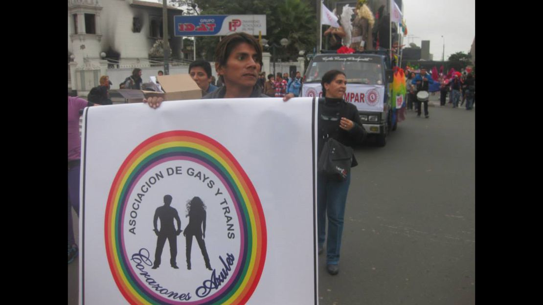Luis Alberto Rojas Marin marches in a parade in Lima, Peru, holding up a sign for an LGBT non-profit. 