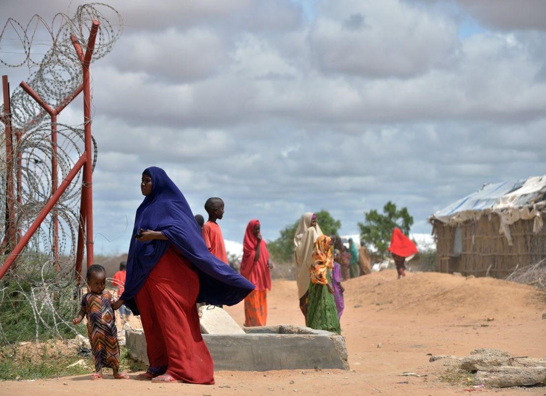A refugee stands with her son just outside a fenced perimeter at Dadaab in May 2015.