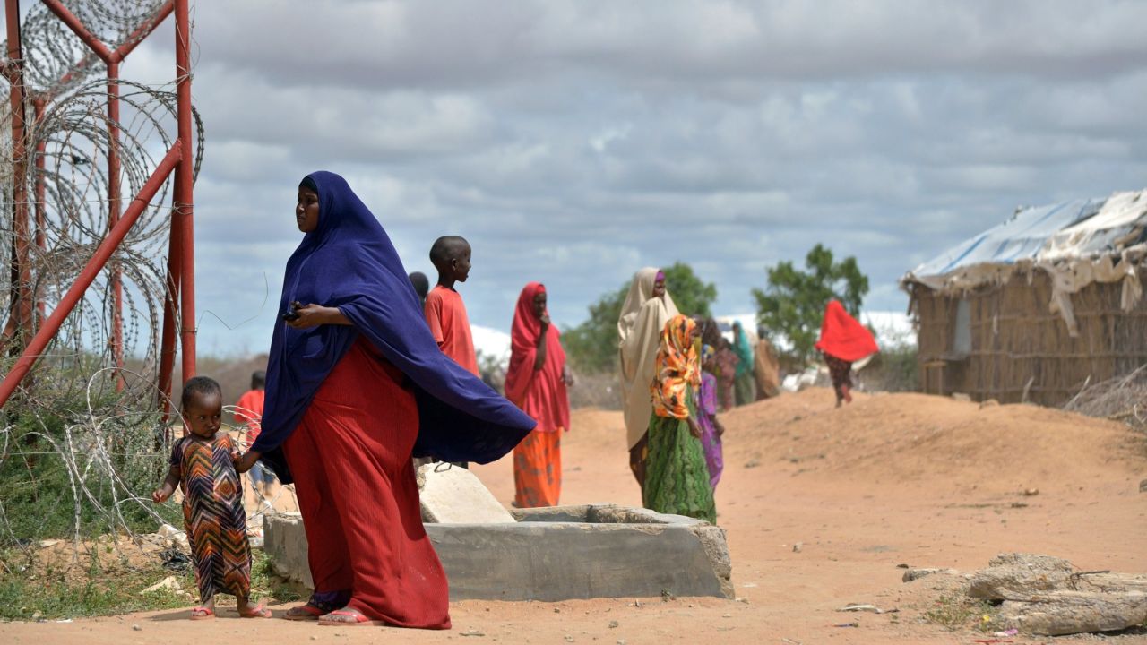 A refugee stands with her son just outside a fenced perimeter at Dadaab in May 2015. 