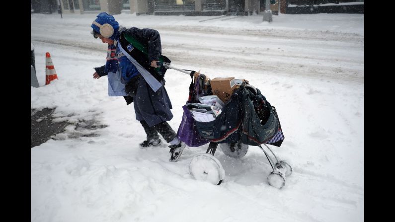 A postal worker drags her mail cart on a snow-covered street in New York on February 9.