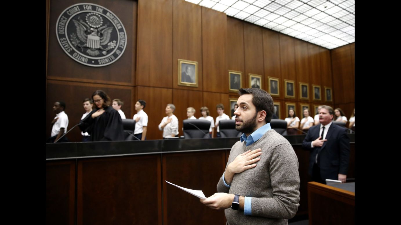 Rohi Atassi, front, leads new US citizens in the Pledge of Allegiance after he and 116 others took the oath of citizenship Tuesday, February 7, in Chicago. Atassi is from Syria.