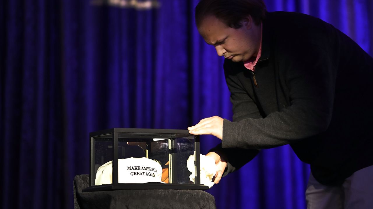 A worker cleans the glass case around the "Make America Great Again" hats on display at Donald Trump's election night party in New York City.