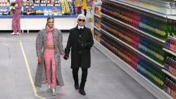 German fashion designer Karl Lagerfeld, flanked by British model Cara Delevingne, acknowledges the audience at the end of Chanel 2014/2015 Autumn/Winter ready-to-wear collection fashion show, on March 4, 2014 at the Grand Palais in Paris.  AFP PHOTO / PATRICK KOVARIK        (Photo credit should read PATRICK KOVARIK/AFP/Getty Images)
