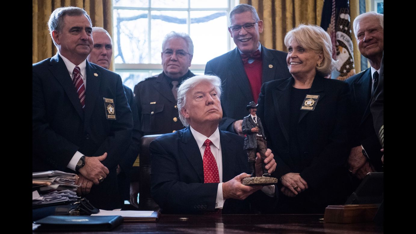 President Trump, sitting in the White House Oval Office, holds a figurine that was given to him by a group of county sheriffs on Tuesday, February 7.